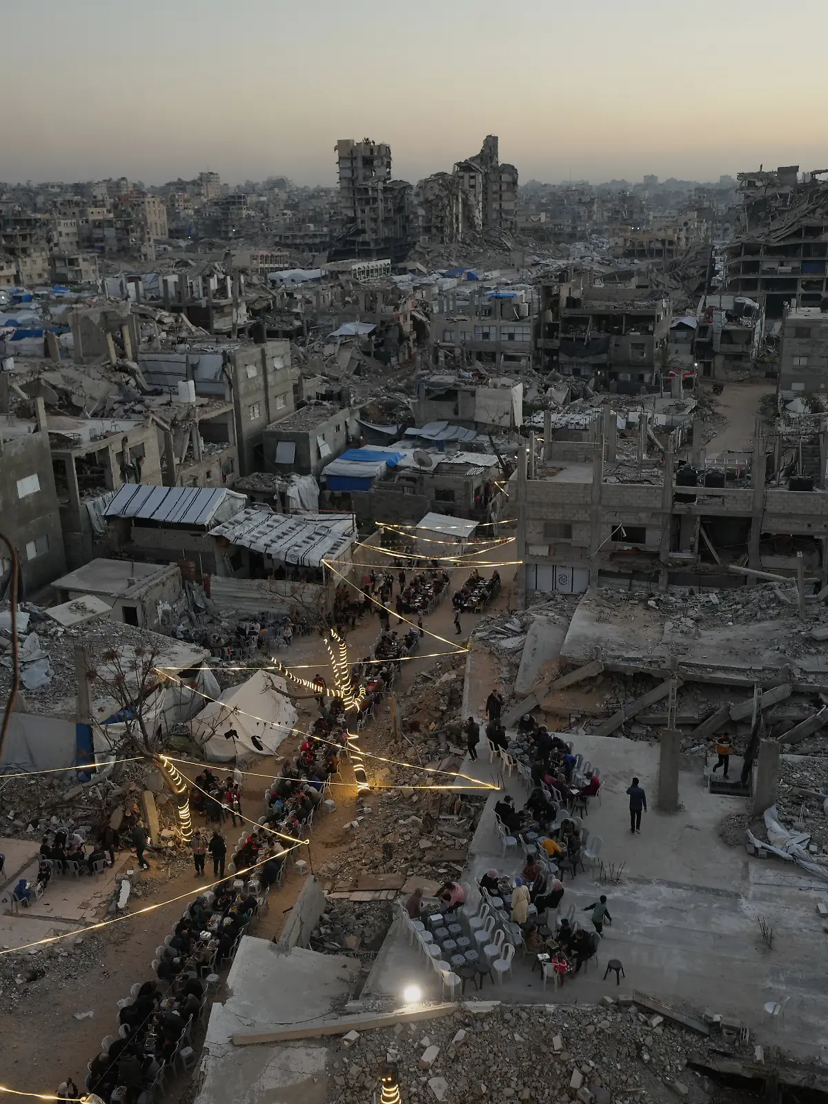 Palästinenser versammeln sich zum Iftar, dem Fastenbrechen, während des muslimischen heiligen Monats Ramadan inmitten der Trümmer zerstörter Gebäude. +++ dpa-Bildfunk +++