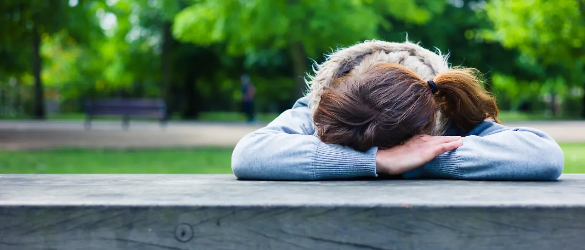 A sad young woman with her head resting on her hands at a table in the park ,model released, Symbolfoto; einer traurig Jung Frau mit her Kopf ausruhenden am her Hände im einer Tisch in der parkähnliche ,model released, Symbolfoto ING_37571_04528 
