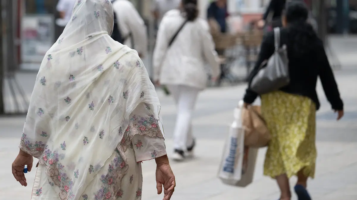 Eine Frau mit einem Kopftuch geht durch die Fußgängerzone von Offenbach. Am Nachmittag wollen sich Vertreter der Ampelkoalition mit der CDU-Opposition über ihre Standpunkte zum Thema Migration austauschen.