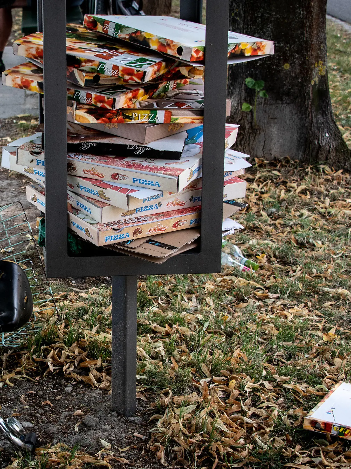 25.07.2020, Bayern, Regensburg: Zahlreiche Pizzakartons sind in einem Stahlgestänge für einen Mülleimer in einer Parkanlage gestapelt und liegen teilweise auf dem Rasen. In städtischen Parks und Grünanlagen stapelt sich der Müll von To-go-Verpackungen. Besonders an den sperrigen Pizzakartons stören sich viele Kommunen. Kann eine Pfandregelung helfen? Foto: Matthias Balk/dpa +++ dpa-Bildfunk +++