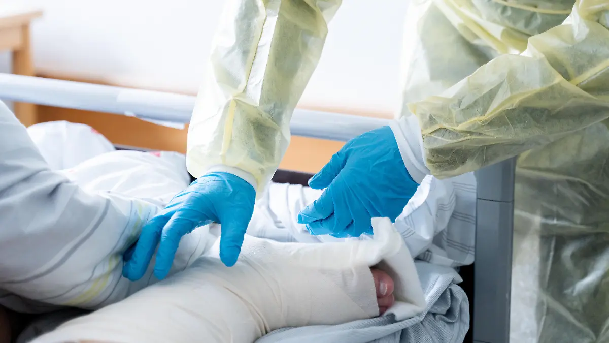 Eine Pflegekraft kümmert sich um einen bewegungseingeschränkten Patienten im Krankenhausbett. Die Szene zeigt professionelle Patientenversorgung in Kliniken und den täglichen Einsatz für medizinische Betreuung und Genesung.