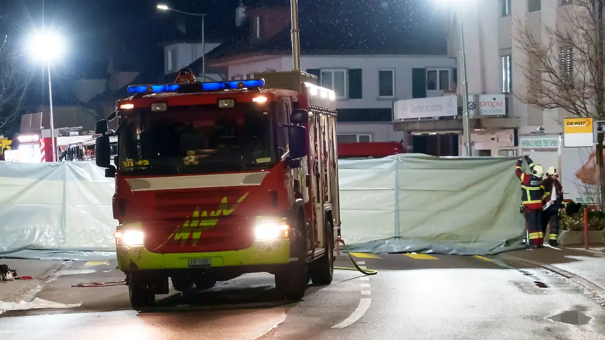 Feuerwehrleute und Polizisten errichten Absperrungen für den Bereich, in dem ein Bus in Brand geraten ist.