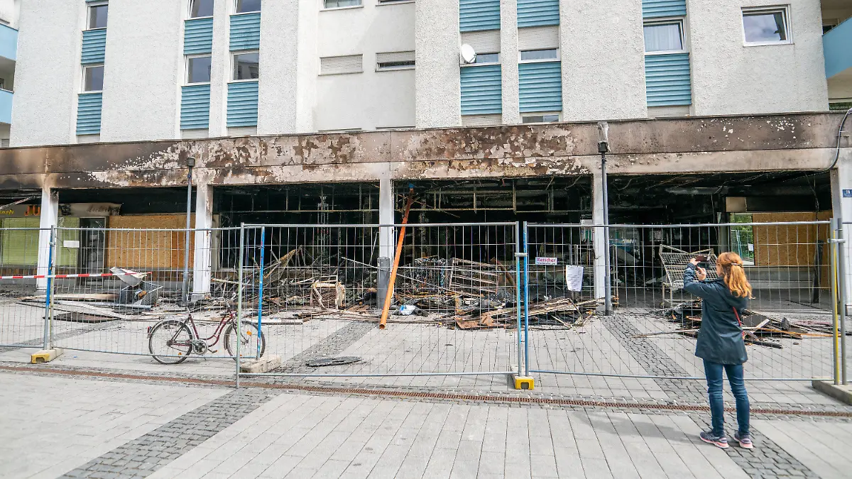 30.04.2020, Bayern, Waldkraiburg: Eine Frau fotografiert die Zerstörung, die ein Brand in einem türkischen Geschäft angerichtet hat. Eine Sonderkommission ermittelt unter der Leitung der Zentralstelle zur Bekämpfung von Extremismus und Terrorismus (ZET) der Generalstaatsanwaltschaft München. Foto: Lino Mirgeler/dpa +++ dpa-Bildfunk +++