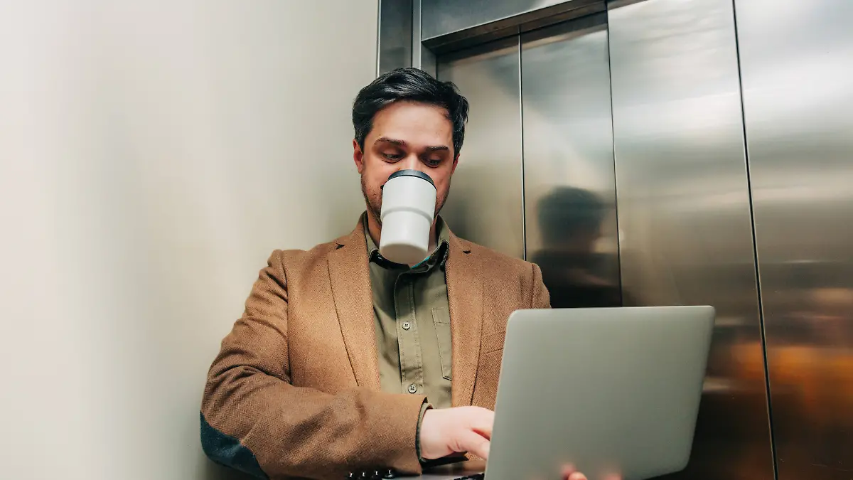 Businessman using laptop and drinking coffee in elevator model released, Symbolfoto, VSNF04636