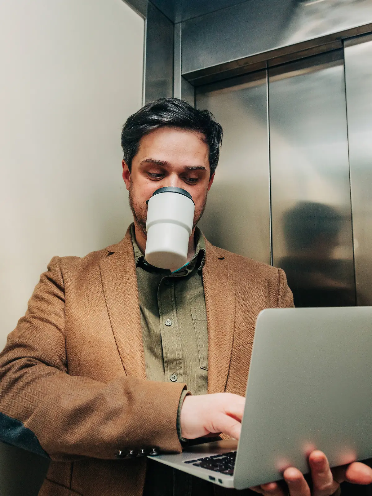 Businessman using laptop and drinking coffee in elevator model released, Symbolfoto, VSNF04636