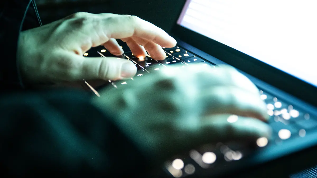 Eine Person tippt mit den Fingern auf einer beleuchteten Laptop-Tastatur.(gestellte Szene) (zu dpa: «Cyberangriffe in Sachsen nehmen zu - so schützen sich Firmen») +++ dpa-Bildfunk +++
