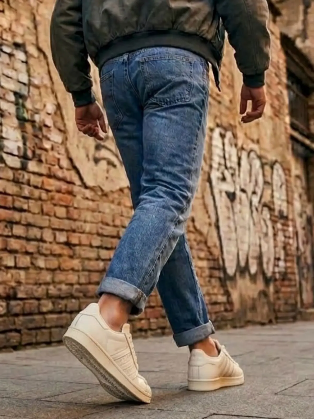 Mann geht auf einer Straße und trägt Retro-Sneaker von Adidas.