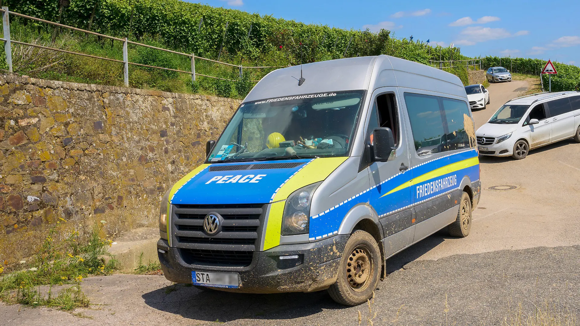 21.07.2021, Rheinland-Pfalz, Ahrweiler: Ein Transporter mit der Aufschrift "Friedensfahrzeug" fährt am Rand des Katastrophengebiets in den Weinbergen entlang. (zu dpa "Polizei hat «Querdenker» im Katastrophengebiet im Blick") Foto: Thomas Frey/dpa +++ dpa-Bildfunk +++