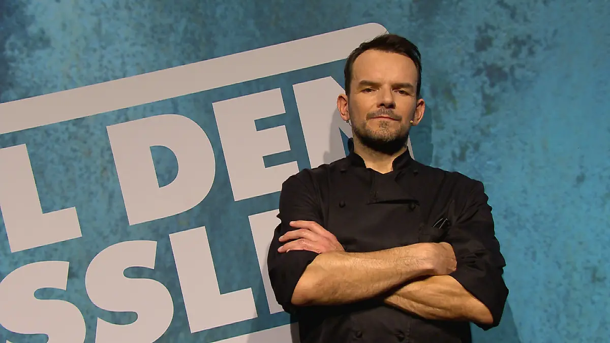 Grill den Henssler: Steffen Henssler steht vor einer blauen Wand mit Sendungslogo