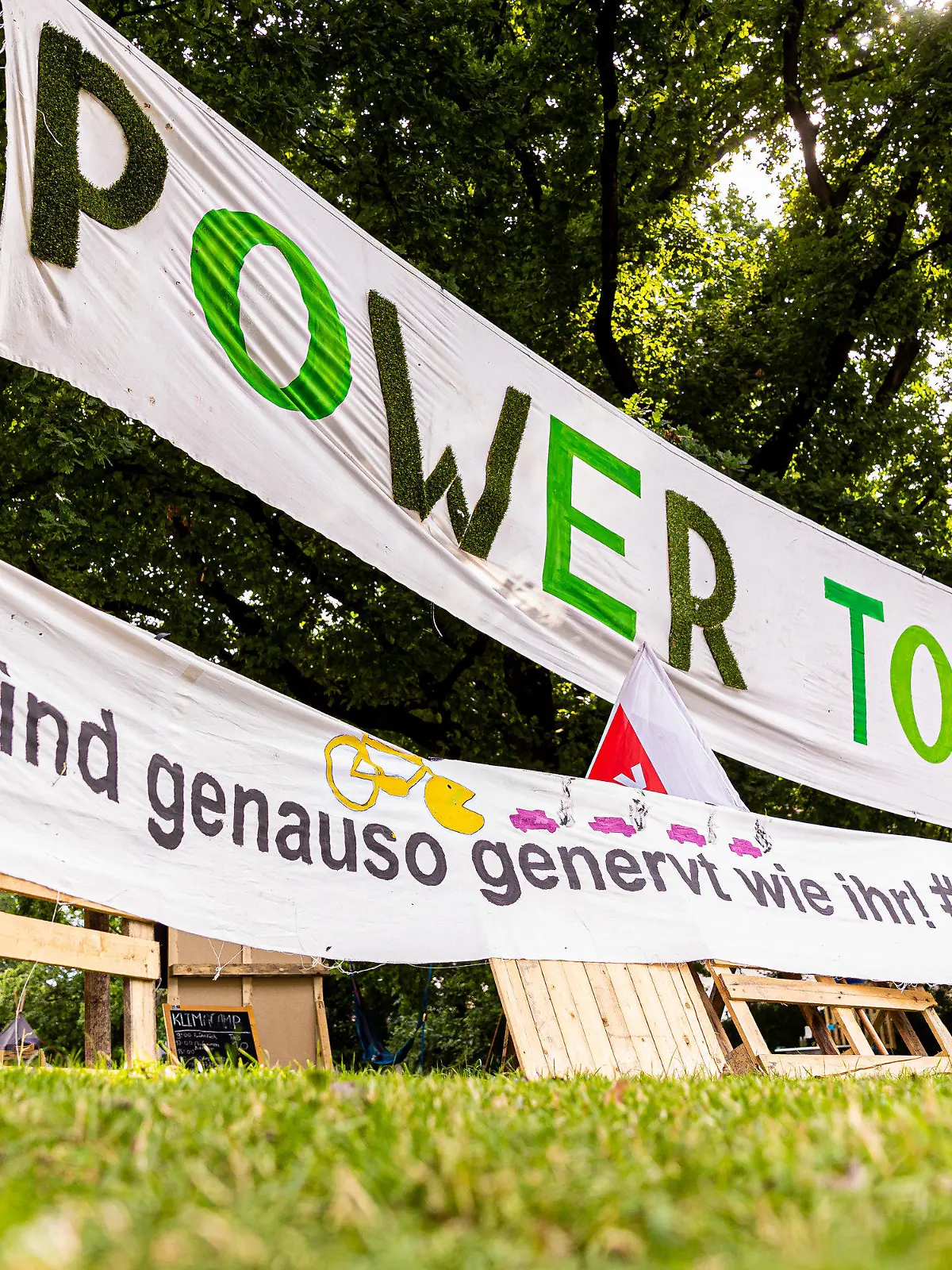 21.07.2021, Niedersachsen, Hannover: Transparente mit der Aufschrift «Power to the people» und «Wir sind genauso genervt wie ihr! #Klimakrise» sind am Rande vom Protestcamp der Bewegung «Fridays for Future» im Maschpark zu sehen. Die Umweltaktivisten fordern mehr Einsatz für den Klimaschutz. Foto: Moritz Frankenberg/dpa +++ dpa-Bildfunk +++