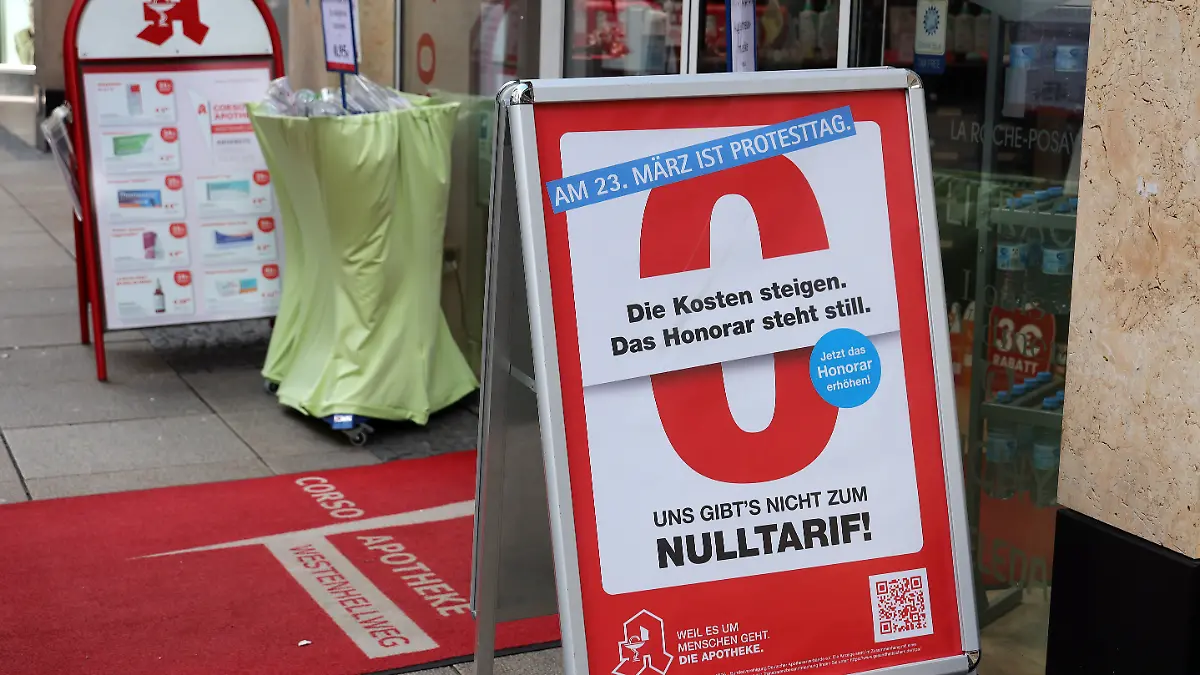 16.03.2026, Deutschland, NRW, Gesundheitswesen, Apotheken, Die Kosten steigen, das Honorar steht still steht auf einem Plakat vor einer Apotheke in Dortmund, bundesweiter Protesttag, Protest, Apotheker-Honorare, Vergütung, Apotheken-Sterben, Schliessungen,