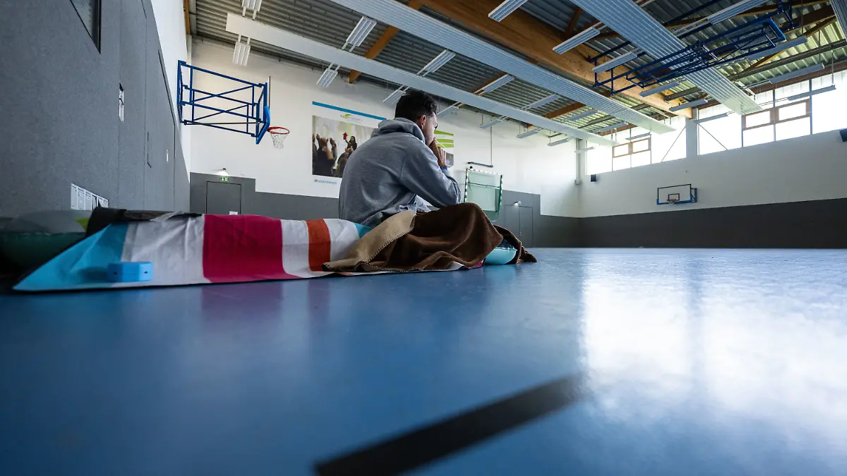 ARCHIV - 03.10.2024, Nordrhein-Westfalen, Münster: Ein Student sitzt in einer Turnhalle auf einer Isomatte. (zu dpa: «Studenten-Mieten bleiben auf Rekordhoch») Foto: Guido Kirchner/dpa +++ dpa-Bildfunk +++