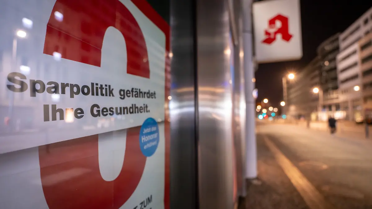 Ein Schild hängt in einer Apotheke und weist auf die Gefahren der Sparpolitik hin.