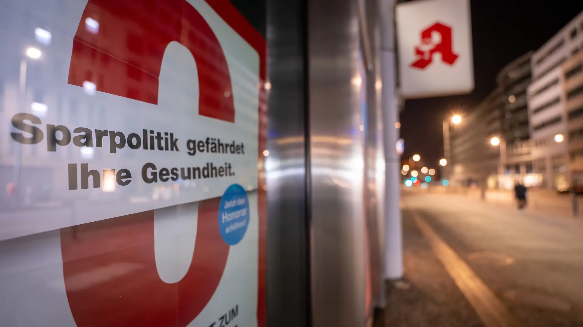 Ein Schild hängt in einer Apotheke und weist auf die Gefahren der Sparpolitik hin.