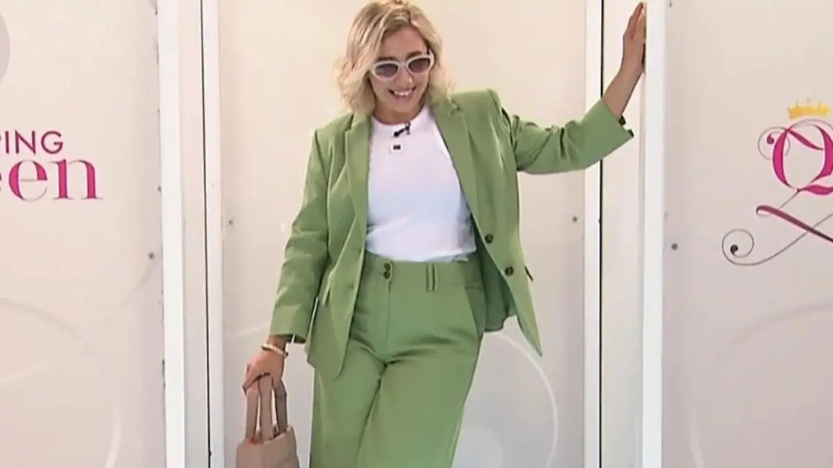 Shopping Queen: Kandidatin Nastia in einem weiten grünen Anzug mit weißem Tanktop, Sonnenbrille, Handtasche und rosafarbenen Sneakern auf dem Laufsteg