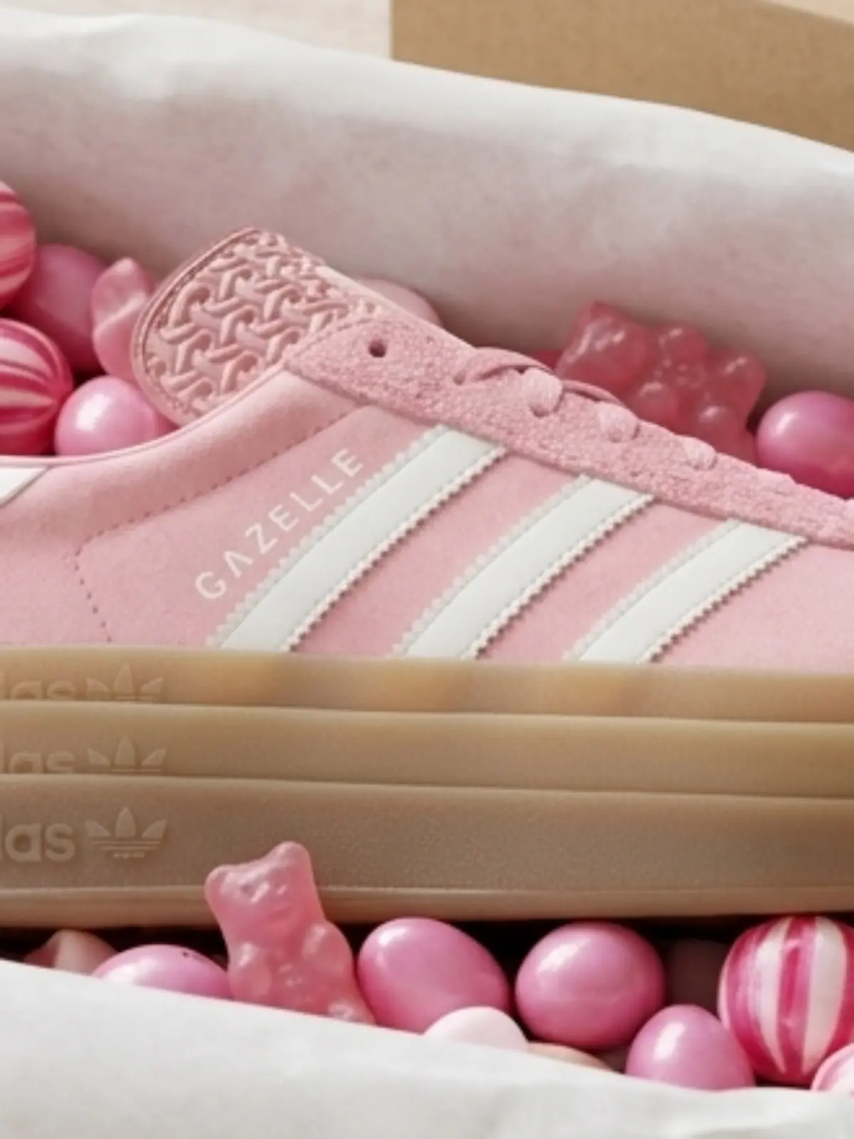 Der Adidas Gazelle Gazelle Bold liegt mit Bonbons in einem Schuhkarton.