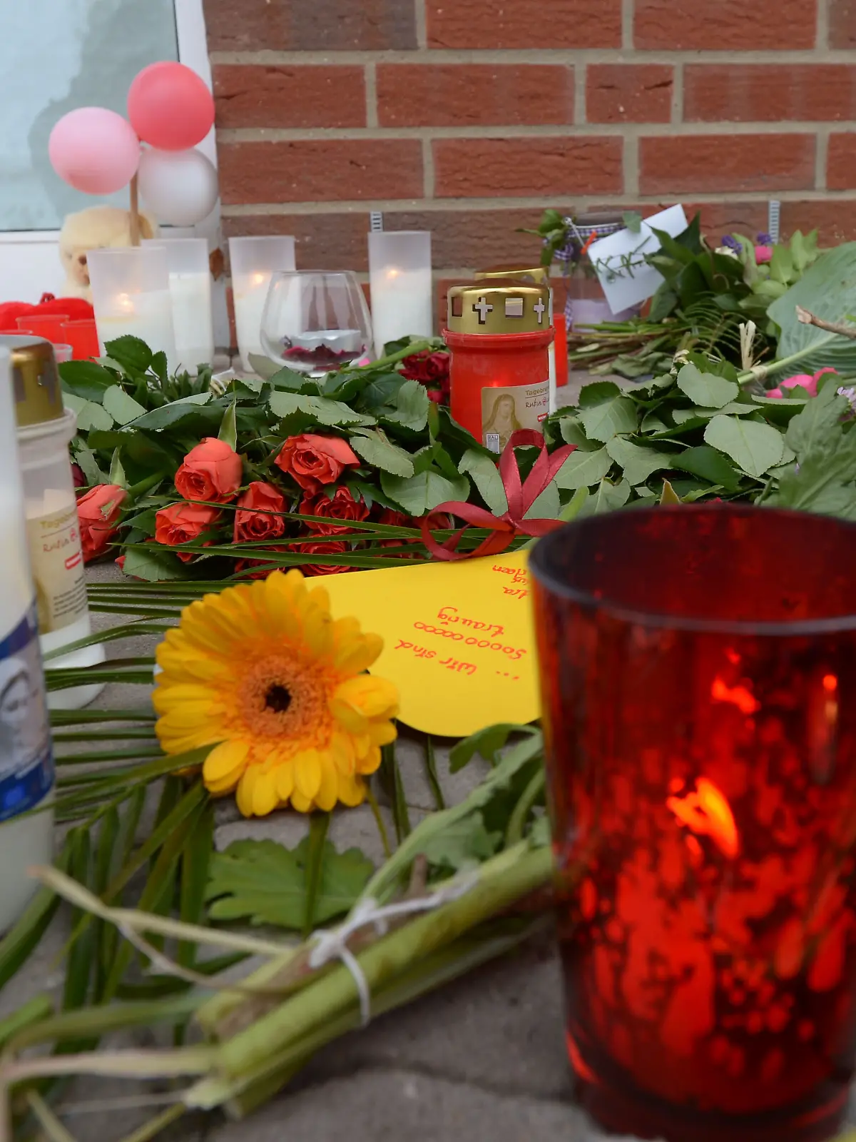 ARCHIV - Blumen, Kerzen und kleine Briefchen liegen am 20.09.2013 vor einem Getränkemarkt in Rethem bei Soltau (Niedersachsen) in dem es zu einem tödlichen Überfall kam. Im Prozess gegen einen Schüler, dem vorgeworfen wird bei einem Überfall auf einen Getränkemarkt eine 23-jährige Frau erstochen zu haben, wird am 24.10.2014 das Urteil erwartet. Foto: Peter Steffen/dpa (zu lni vom 24.10.2014) +++ dpa-Bildfunk +++