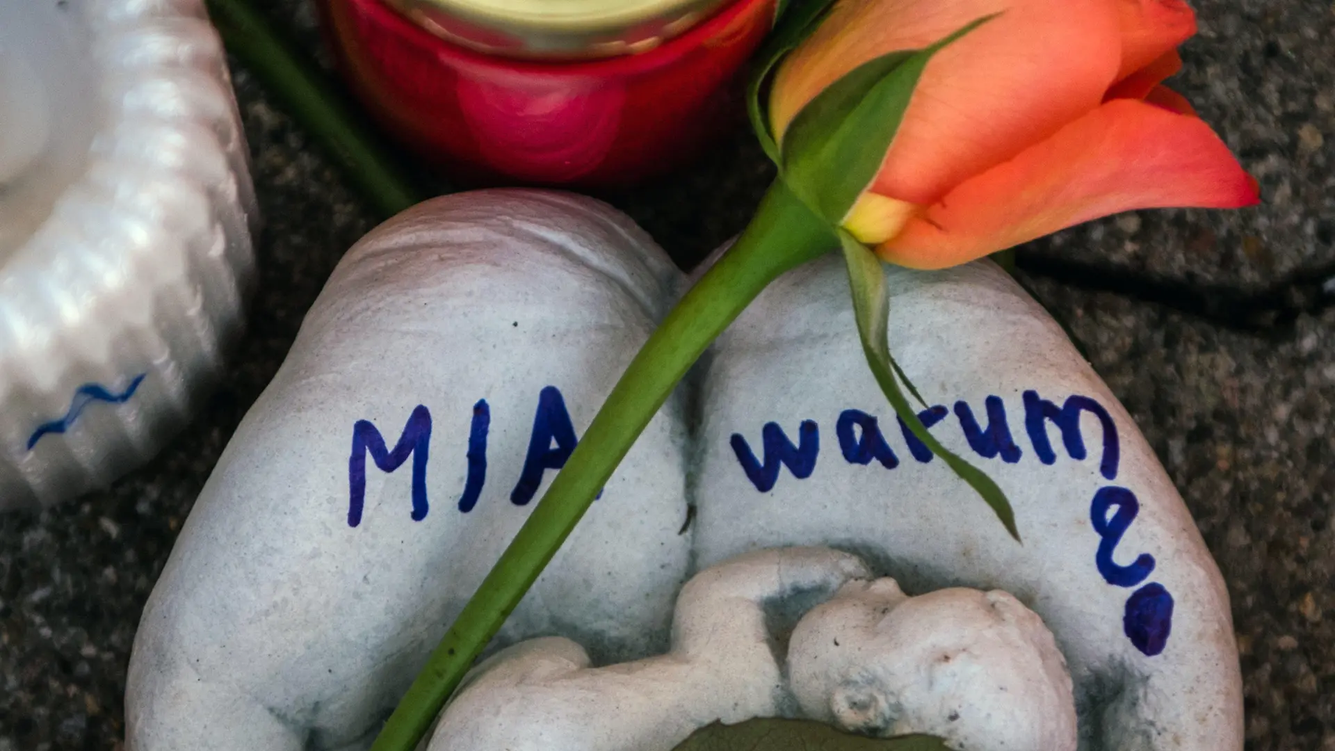 ARCHIV - 28.12.2017, Rheinland-Pfalz, Kandel: Eine Skulptur in Form zweier Handflächen mit der Aufschrift "Mia warum?" und eine Rose liegen vor dem Drogeriemarkt, in dem ein 15-jähriges Mädchen von ihrem Ex-Freund erstochen wurde. (zu dpa «Mordanklage nach tödlichem Messerangriff auf Jugendliche in Kandel» vom 18.04.2018)) Foto: Andreas Arnold/dpa +++ dpa-Bildfunk +++