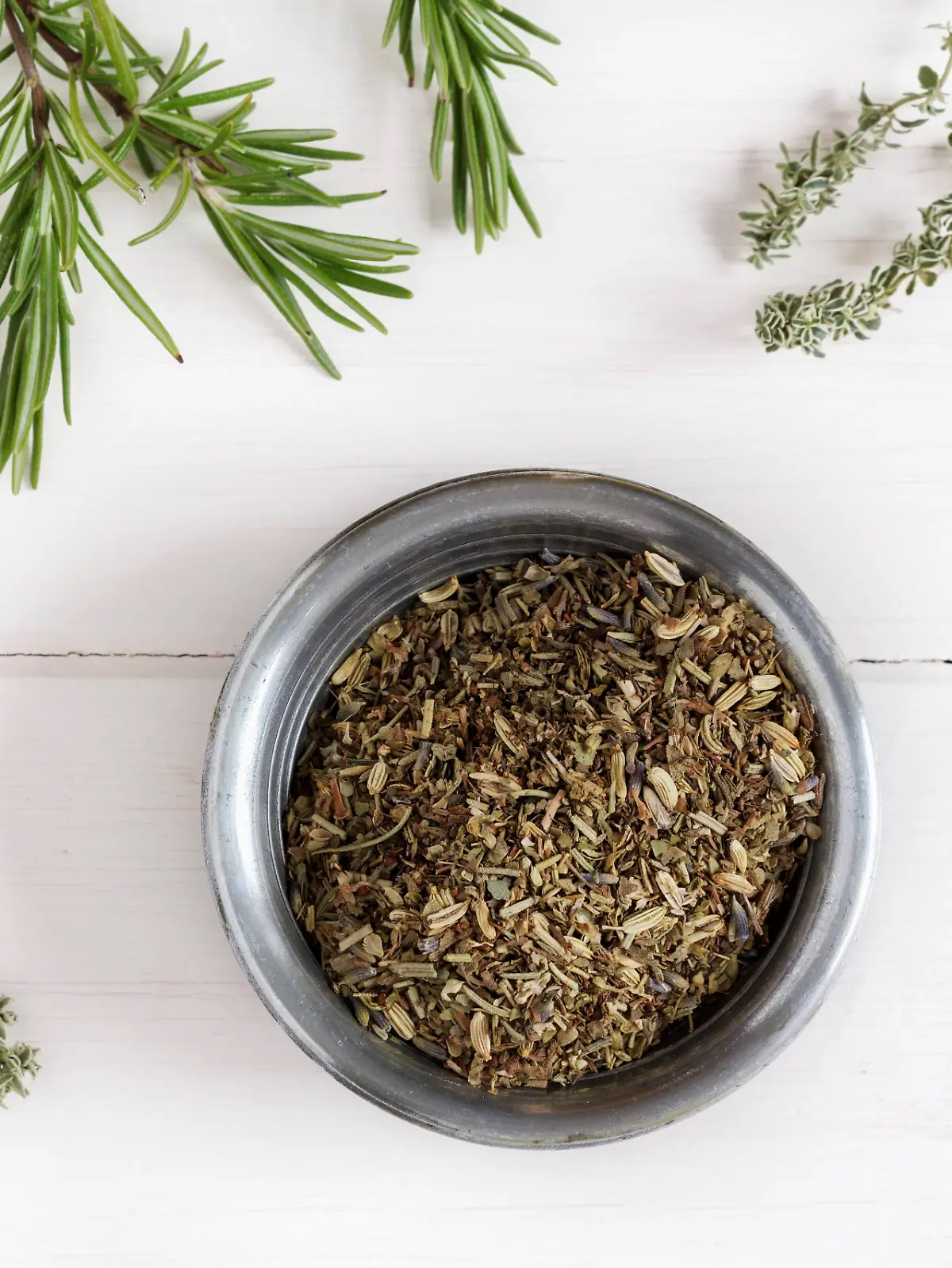 Kräuter der Provence im Schälchen umgeben von frischen Kräutern