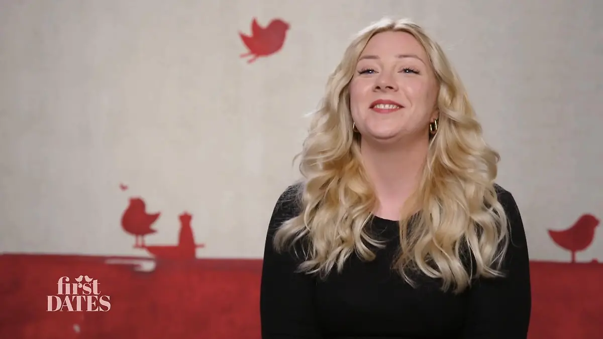 First Dates – Ein Tisch für zwei: Fröhlich strahlende junge Frau mit blonden Locken und schwarzem Oberteil