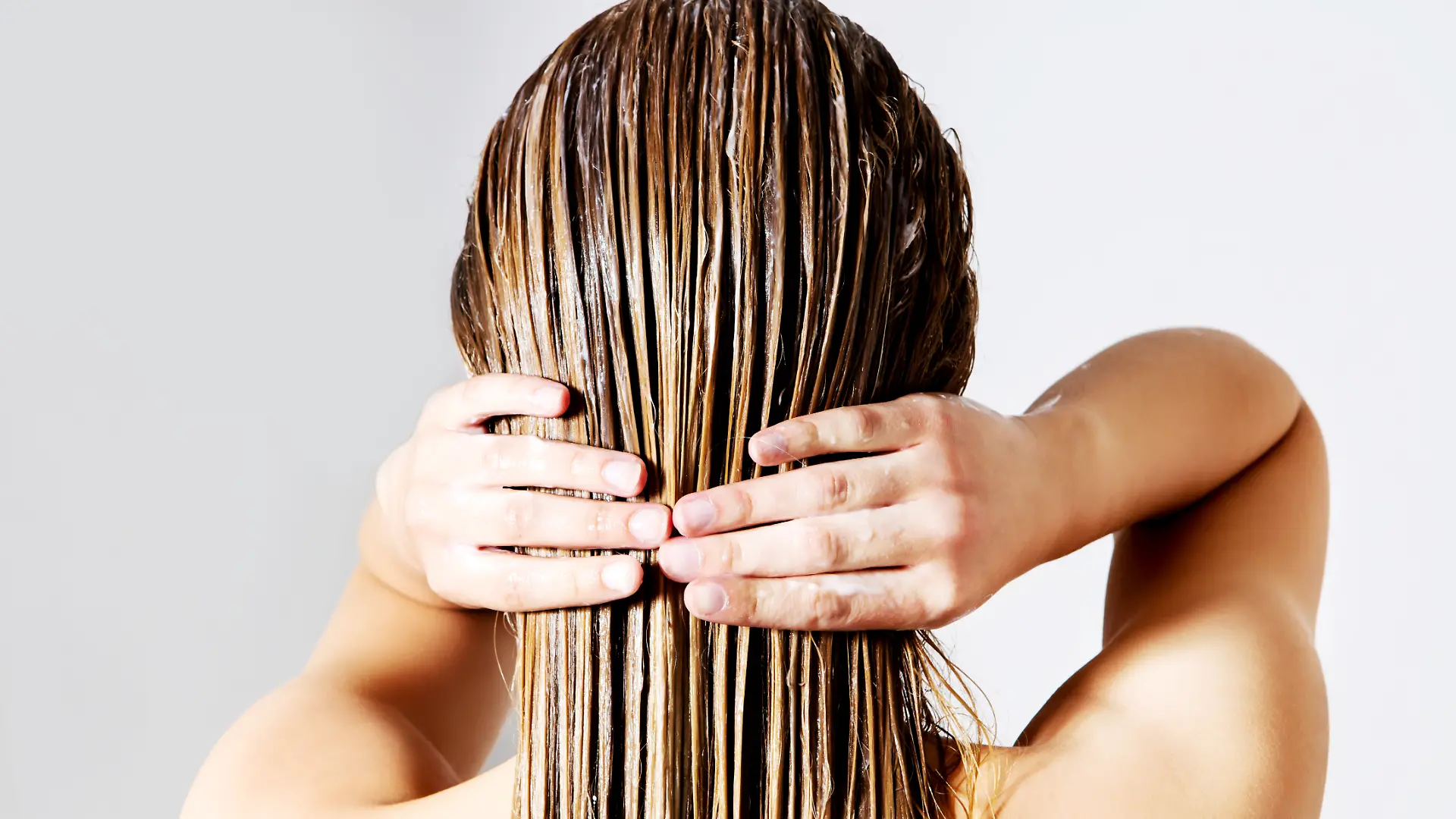 Blonde Frau trägt Haarspülung auf