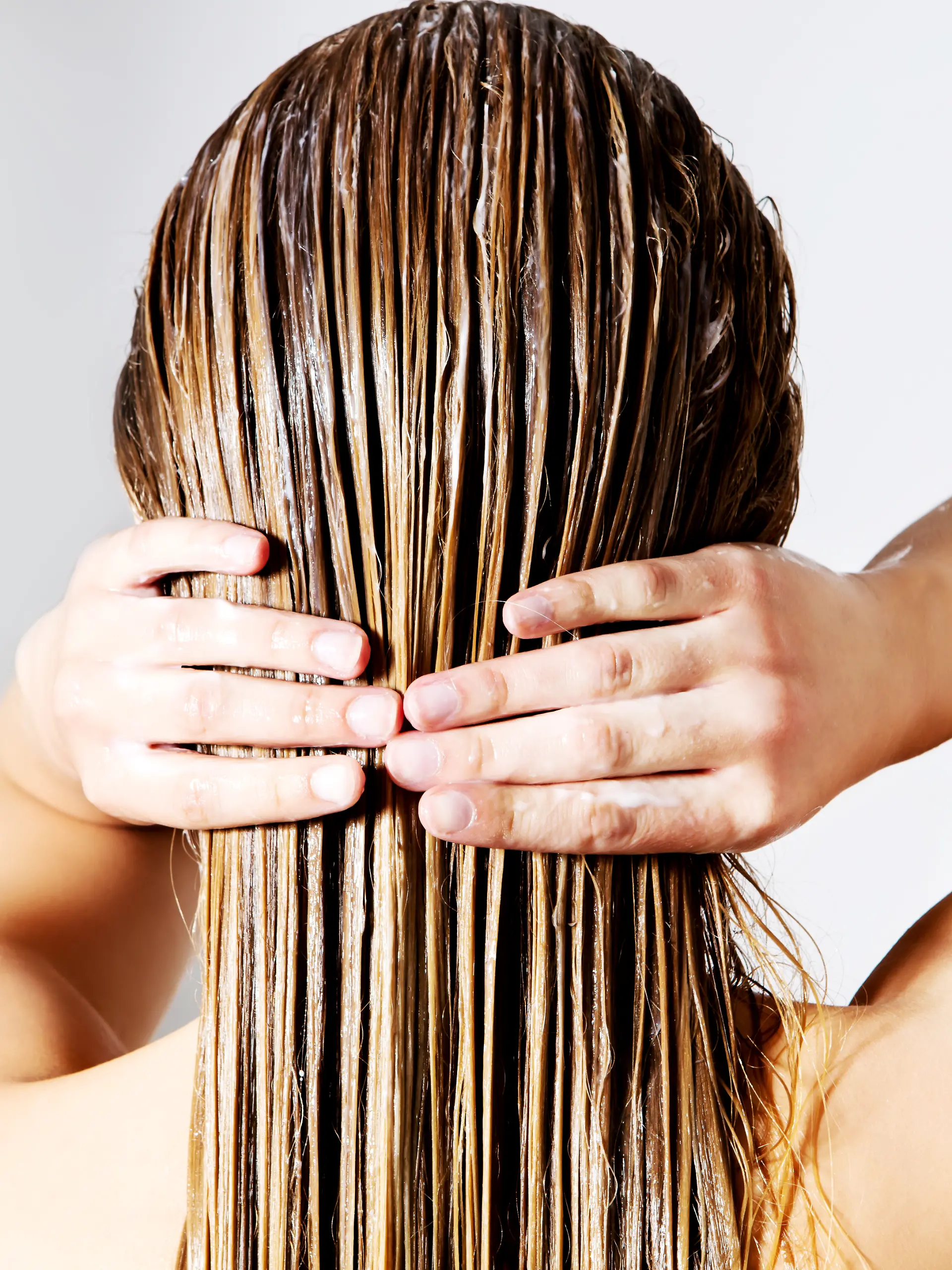 Blonde Frau trägt Haarspülung auf