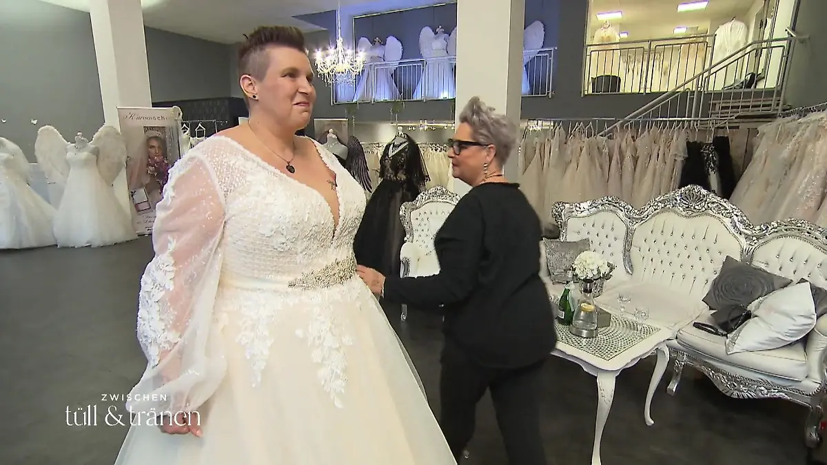 Zwischen Tüll und Tränen: Braut Marina betrachtet sich in einem tief ausgeschnittenen Brautkleid