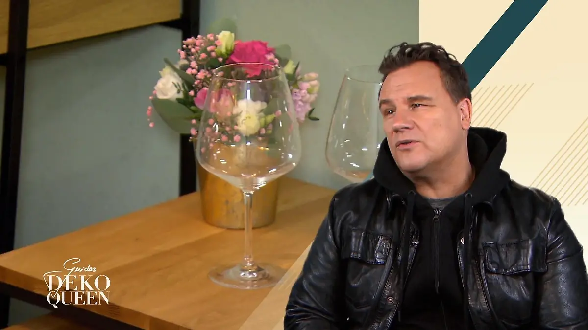 Guidos Deko Queen: Guido Maria Kretschmer schaut auf Weingläser vor einem kleinen Blumenstrauß auf einem Holztisch