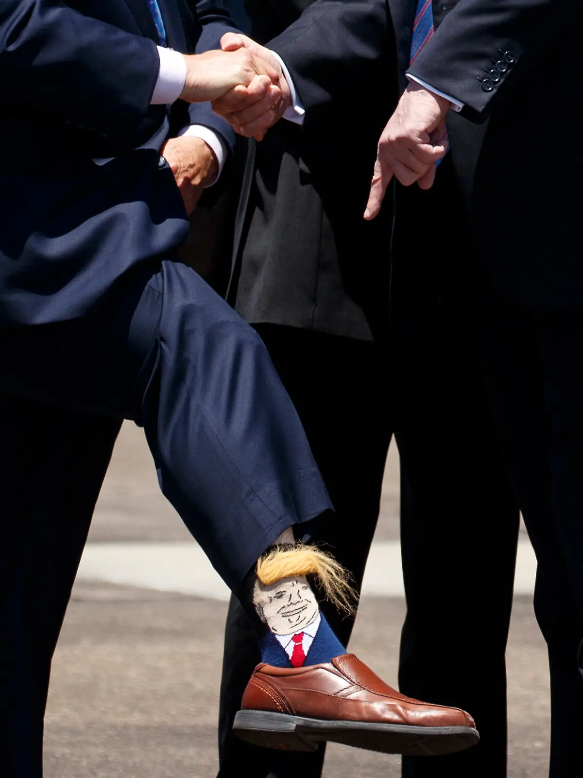 Donald Trump (r), Präsident der USA, zeigt auf eine Socke von Billy Nungesser, Vizegouverneur des Staates Louisiana, der bei seiner Ankunft am Chennault International Airport ein Hosenbein hochzieht und dabei eine Socke mit einem Konterfei von Trump entblößt. (zu dpa: «Duma-Abgeordnete in USA bekommen Trump-Socken als Geschenk») +++ dpa-Bildfunk +++