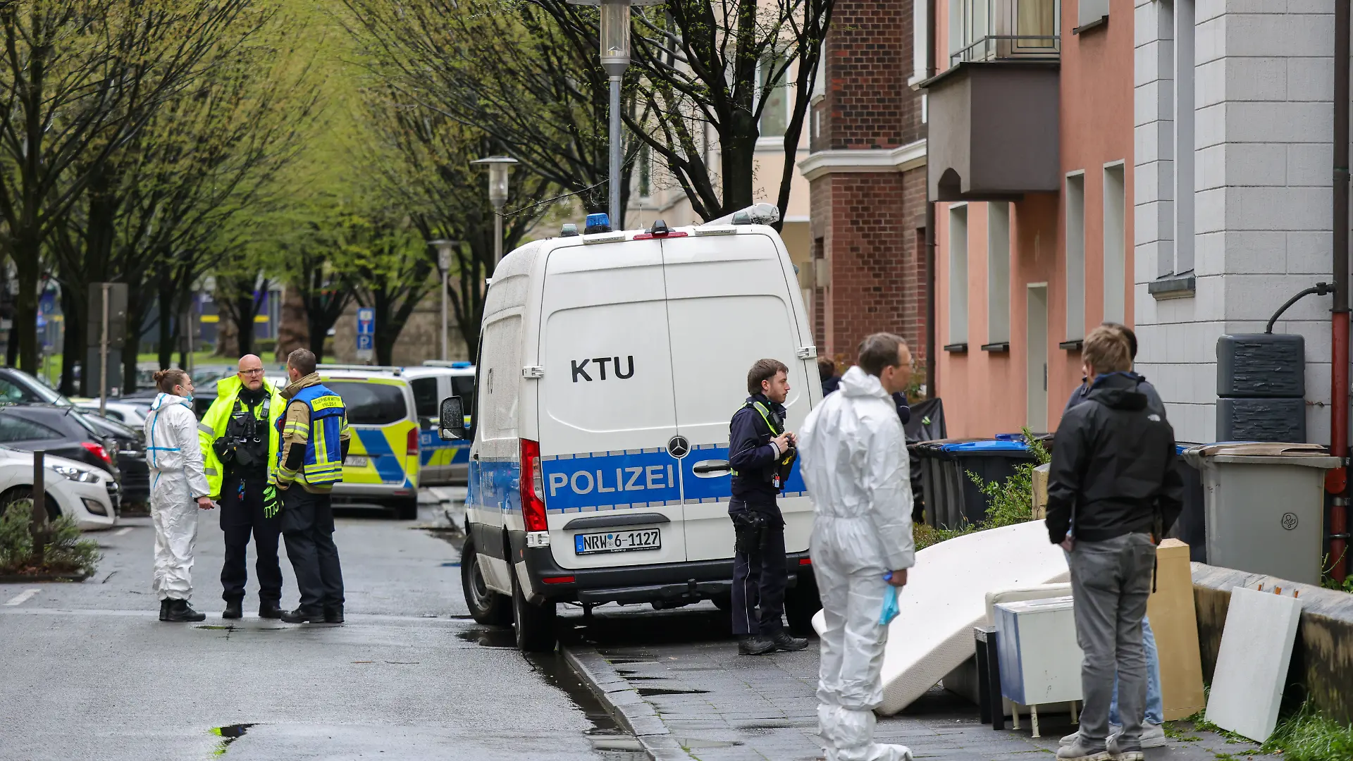 Vor dem Mehrfamilienhaus der Familie stehen Beamte der Polizei auf dem Gehweg und der Straße. +++ dpa-Bildfunk +++