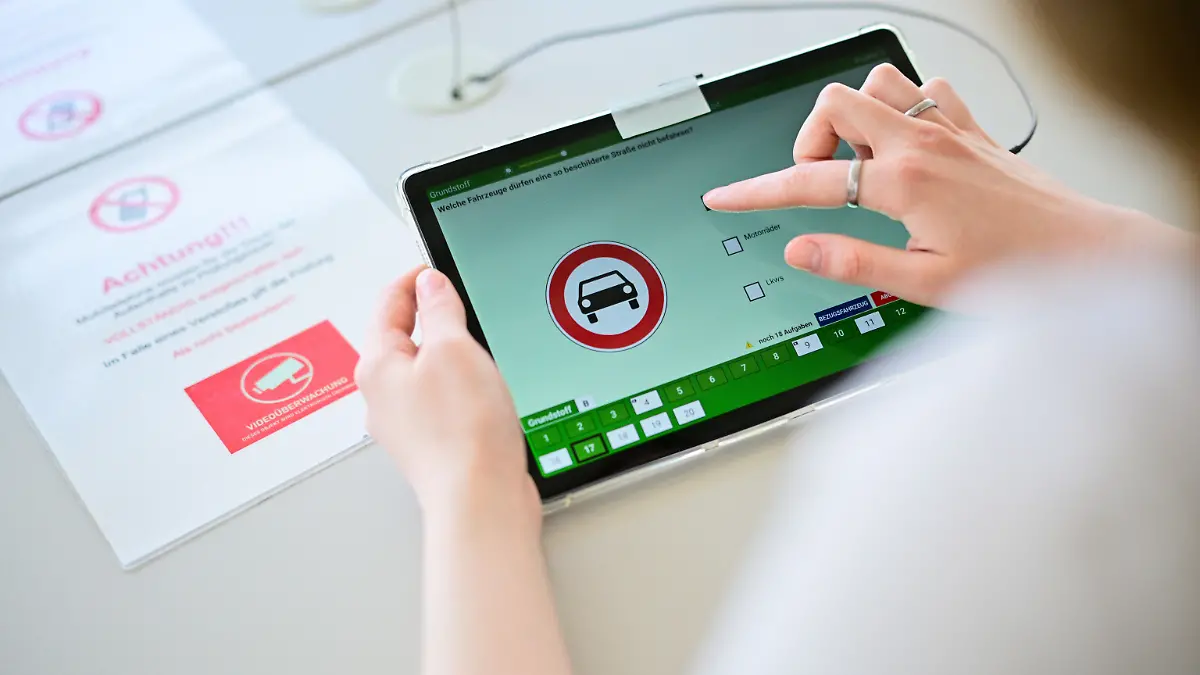 ILLUSTRATION - 16.04.2025, Berlin: Eine Frau beantwortet in Berlin eine Frage der theoretischen Prüfung des Führerscheins. (Gestellte Szene). Neben ihr liegt ein Zettel, der auf die Videoüberwachung und das Nutzungsverbot von Smartphones hinweist. (zu dpa: «Mit Mini-Kamera zum Führerschein: Betrug auf Rekordniveau») Foto: Sebastian Gollnow/dpa +++ dpa-Bildfunk +++