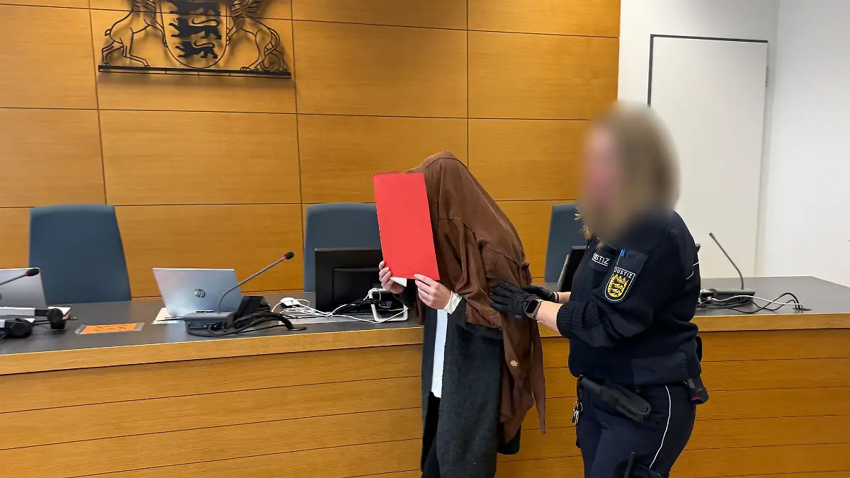 Die Angeklagte wird von einer Justizbeamtin in den Gerichtssaal geführt. Die 41-Jährige aus Landstuhl steht wegen gewerbsmäßigem Betrugs und Urkundenfälschung vor dem Landgericht Heidelberg. Die Frau soll jahrelang ohne entsprechende Qualifikation an Privatschulen in Baden-Württemberg und Saarland Mathe, Physik und Chemie unterrichtet.