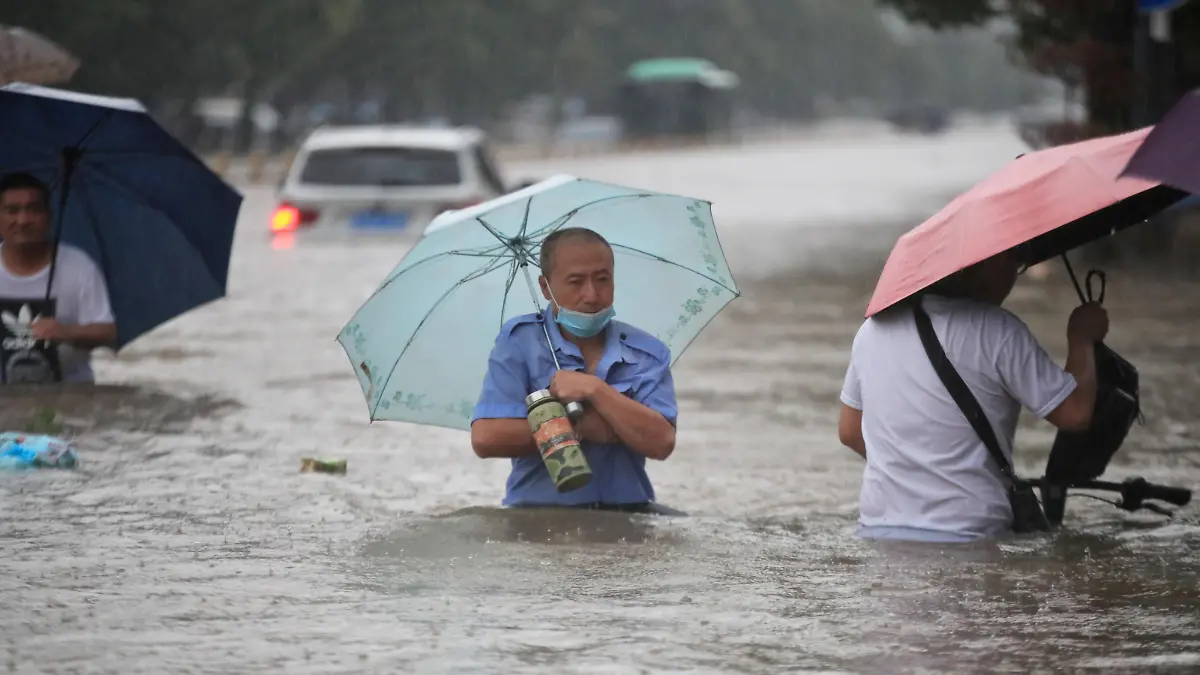 Residents wade through floodwaters on a flooded road amid heavy rainfall in Zhengzhou, Henan province, China July 20, 2021. Picture taken July 20, 2021. China Daily via REUTERS ATTENTION EDITORS - THIS IMAGE WAS PROVIDED BY A THIRD PARTY. CHINA OUT.