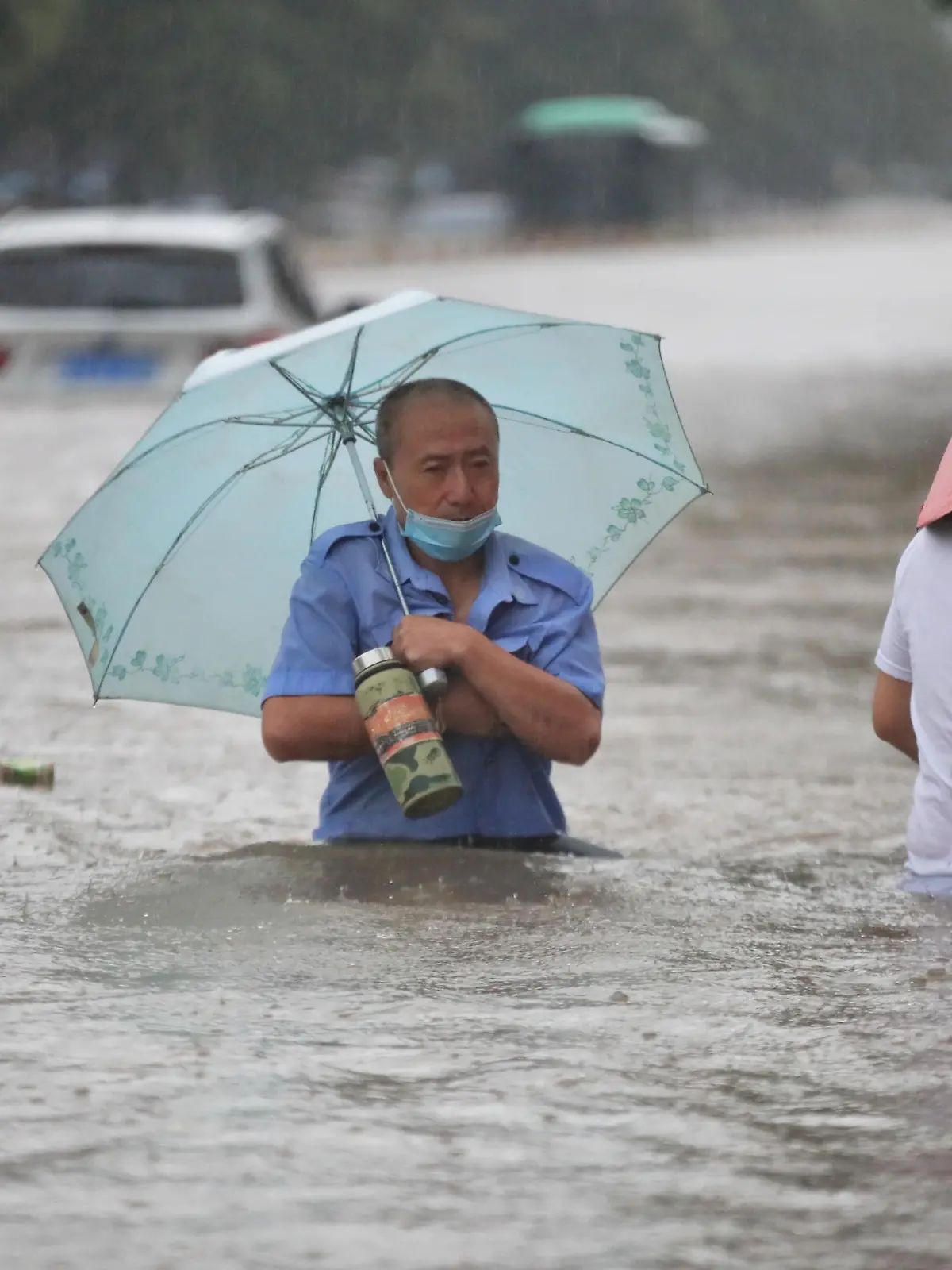Residents wade through floodwaters on a flooded road amid heavy rainfall in Zhengzhou, Henan province, China July 20, 2021. Picture taken July 20, 2021. China Daily via REUTERS  ATTENTION EDITORS - THIS IMAGE WAS PROVIDED BY A THIRD PARTY. CHINA OUT.