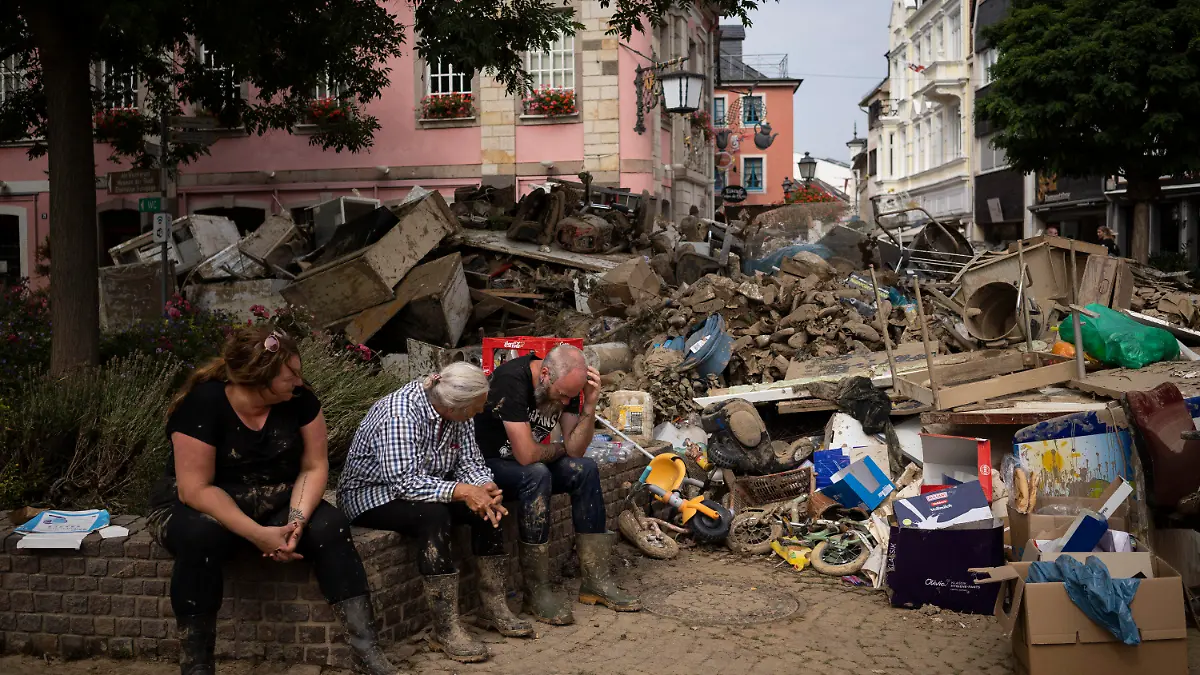 People rest from cleaning up the debris of the flood disaster in Bad Neuenahr-Ahrweiler, Germany, Monday July 19, 2021. More than 180 people died when heavy rainfall turned tiny streams into raging torrents across parts of western Germany and Belgium, and officials put the death toll in Ahrweiler county alone at 110. (AP Photo/Bram Janssen)