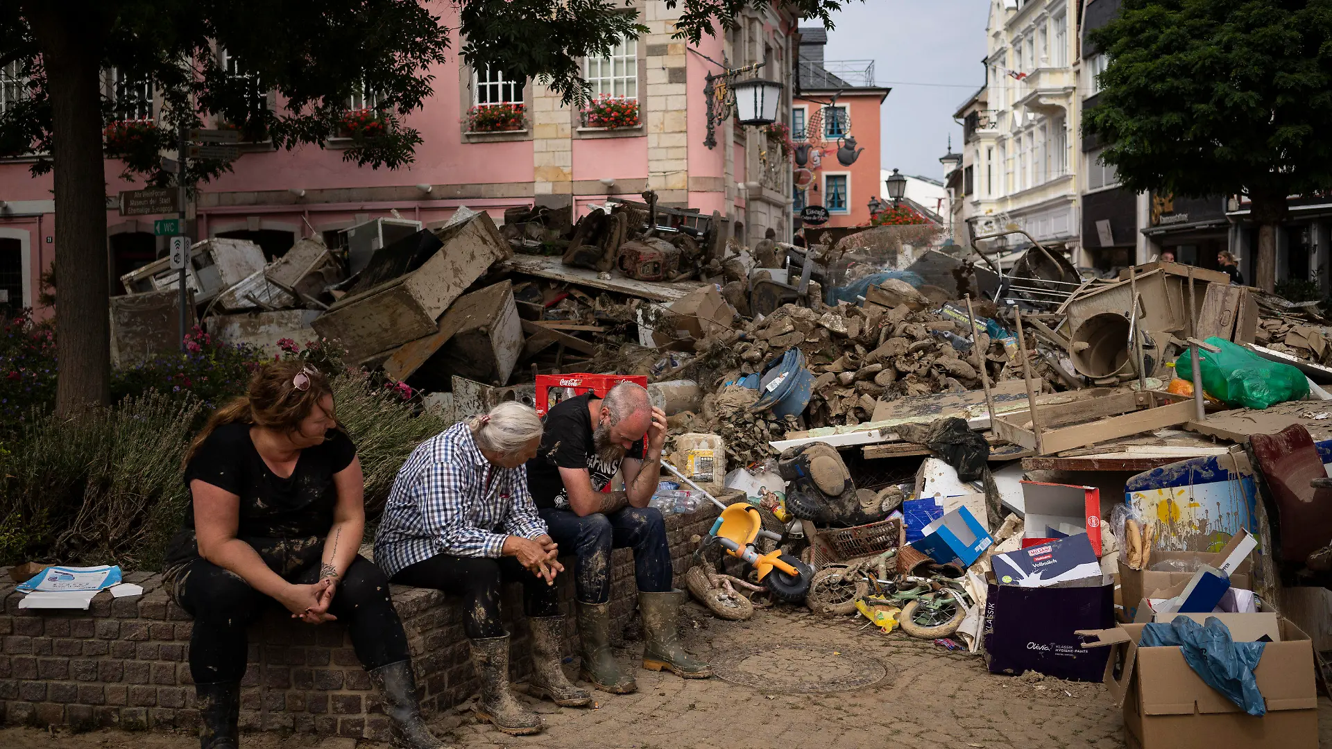 People rest from cleaning up the debris of the flood disaster in Bad Neuenahr-Ahrweiler, Germany, Monday July 19, 2021. More than 180 people died when heavy rainfall turned tiny streams into raging torrents across parts of western Germany and Belgium, and officials put the death toll in Ahrweiler county alone at 110. (AP Photo/Bram Janssen)