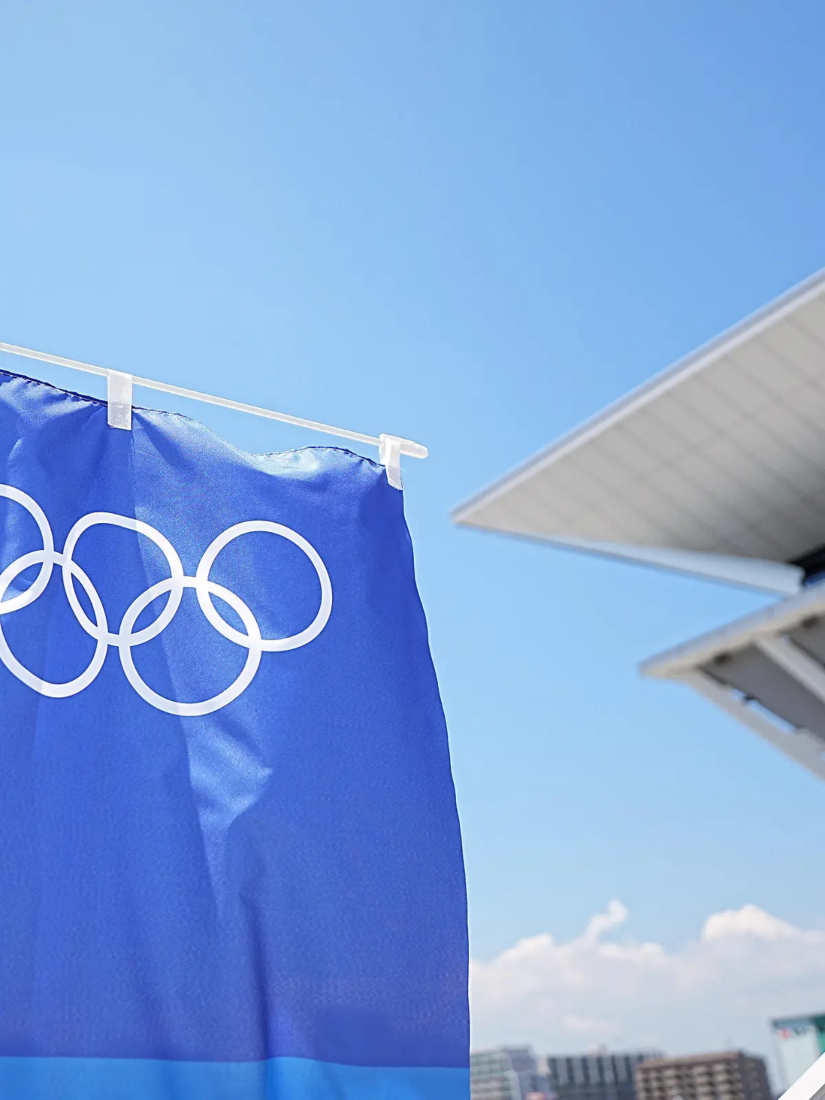 19.07.2021, Japan, Tokio: Eine Fahne mit den Olympischen Ringen hängt vor einem Gebäude. Die Olympischen Spiele 2020 Tokio finden vom 23.07.2021 bis zum 08.08.2021 statt. Foto: Michael Kappeler/dpa +++ dpa-Bildfunk +++