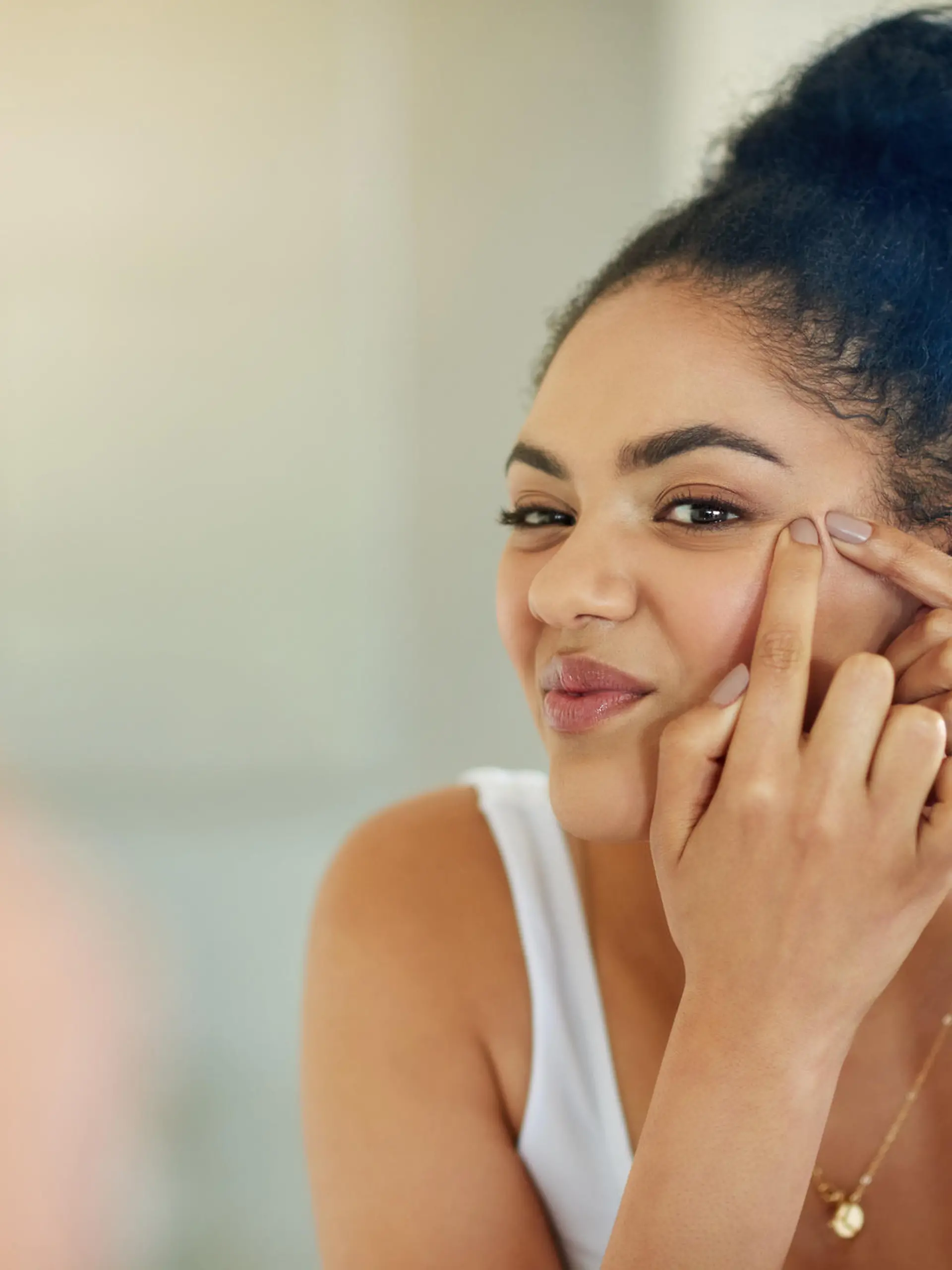Shot of a young woman squeezing a pimple in front of the bathroom mirror