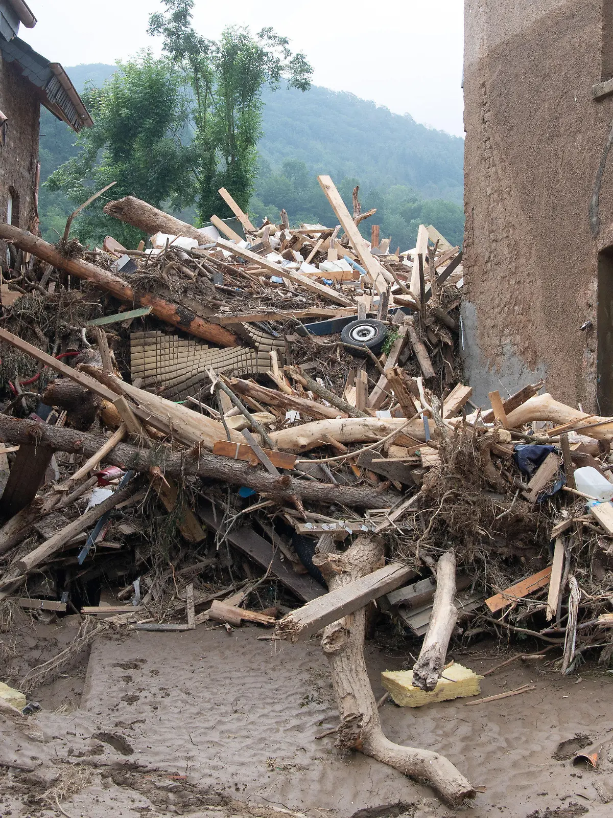 19.07.2021, Rheinland-Pfalz, Altenahr: Meterhoch türmt sich angespülter Unrat zwischen zwei Gebäuden in Altenahr. Zahlreiche Häuser in dem Ort wurden komplett zerstört oder stark beschädigt, es gibt zahlreiche Todesopfer. Foto: Boris Roessler/dpa +++ dpa-Bildfunk +++