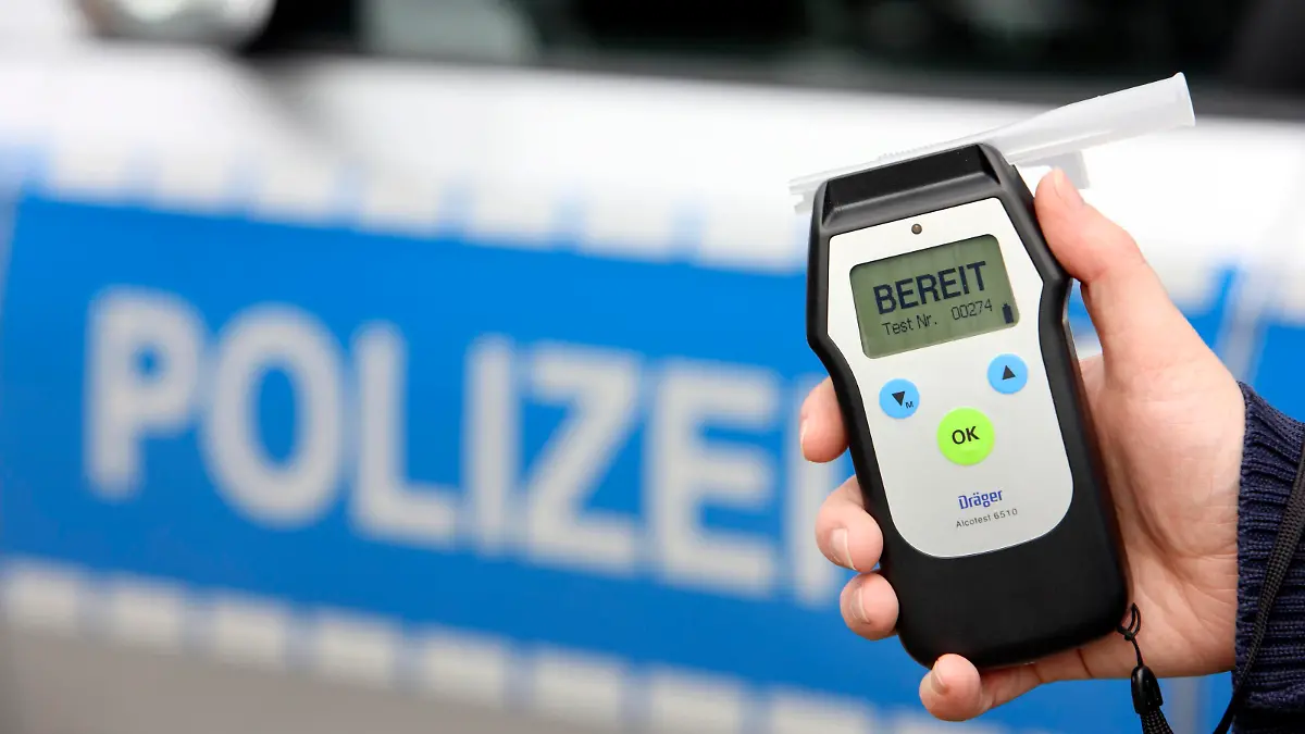 Polizist mit Atemalkohol-Messgerät zur Überprüfung der Fahrtüchtigkeit eines Autofahrers