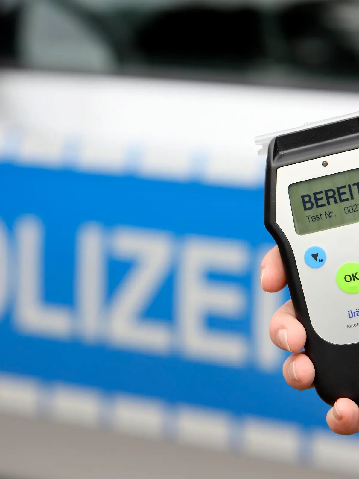 Polizist mit Atemalkohol-Messgerät zur Überprüfung der Fahrtüchtigkeit eines Autofahrers