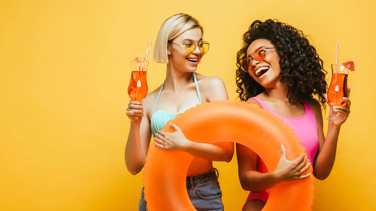 Zwei Frauen mit Cocktails und Schwimmringen in der Hand.