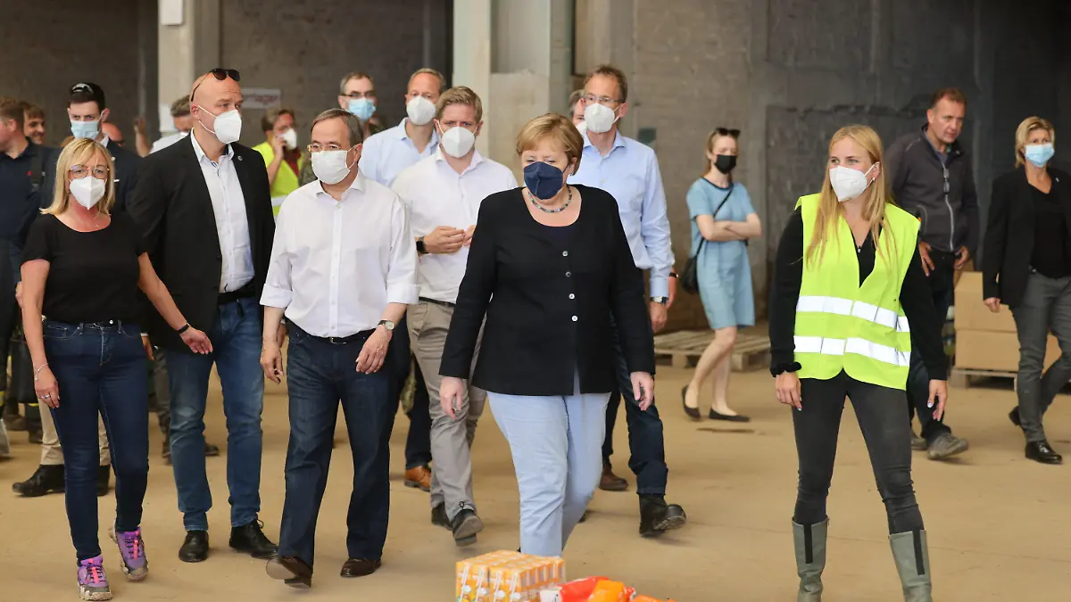 20.07.2021, Nordrhein-Westfalen, Bad Münstereifel: Bundeskanzlerin Angela Merkel (CDU, M)und der Ministerpräsident von Nordrhein-Westfalen Armin Laschet (CDU, 3.v.l) besichtigen ein Lager mit Lebensmitteln bei ihrem Besuch im vom Hochwasser betroffenen Gebiet von Bad Münstereifel. Foto: Oliver Berg/dpa-Pool/dpa +++ dpa-Bildfunk +++