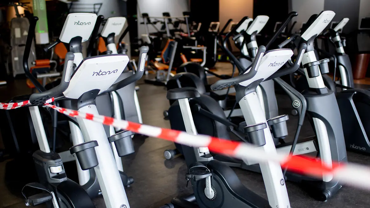 06.11.2020, Niedersachsen, Langenhagen: Ein rot-weißes Flatterband ist an Fahrradtrainern befestigt, die in einem Fitnessstudio stehen. Fitnessstudios in Niedersachsen müssen vorerst weiter geschlossen bleiben. Anträge auf vorläufige Außervollzugsetzung der Schließung seien abgelehnt worden, teilte das Niedersächsische Oberverwaltungsgericht am Freitag in Lüneburg mit. Foto: Hauke-Christian Dittrich/dpa +++ dpa-Bildfunk +++