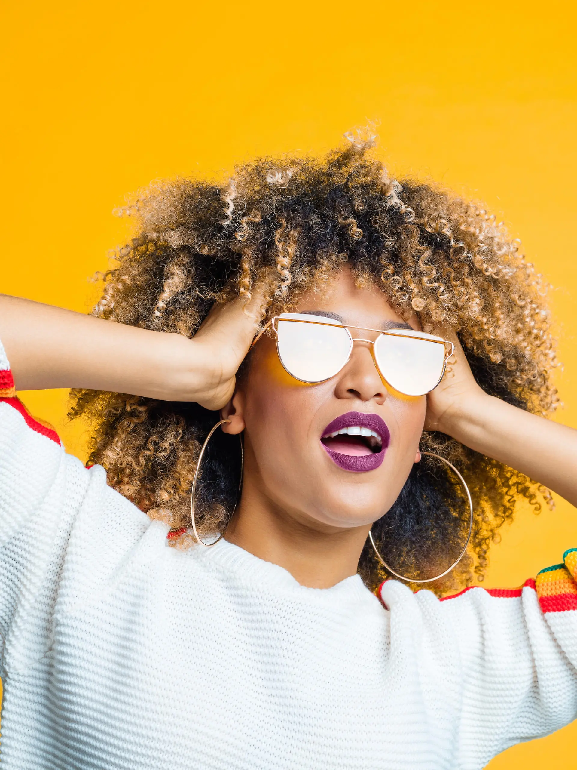 Sternzeichen Löwe: Frau mit Afro trägt Sonnenbrille.