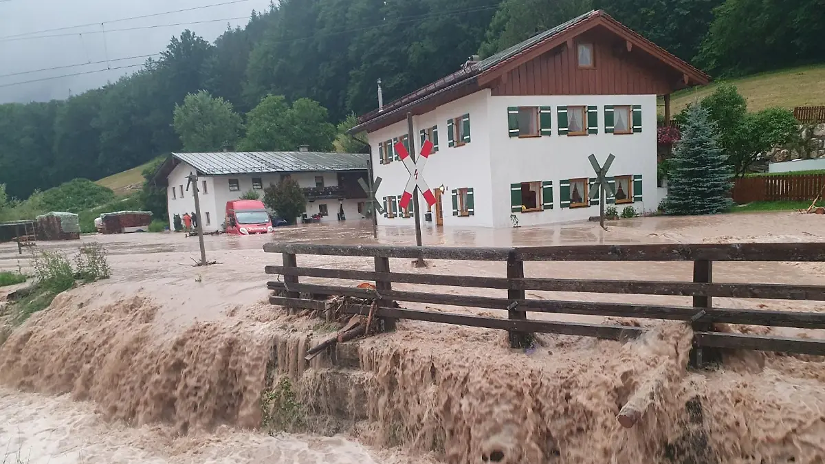 dpatopbilder - 17.07.2021, Bayern, Bischofswiesen: Wasser fließt über einen Platz vor einem Haus. Der Landkreis Berchtesgadener Land hat nach starkem Regen wegen Hochwassers den Katastrophenfall ausgerufen. Foto: Kilian Pfeiffer/dpa +++ dpa-Bildfunk +++
