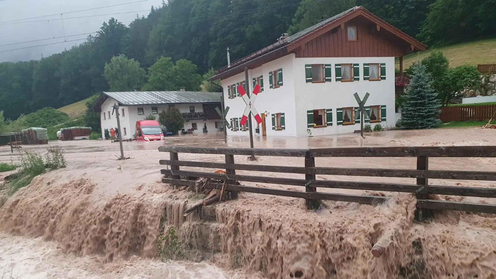 dpatopbilder - 17.07.2021, Bayern, Bischofswiesen: Wasser fließt über einen Platz vor einem Haus. Der Landkreis Berchtesgadener Land hat nach starkem Regen wegen Hochwassers den Katastrophenfall ausgerufen. Foto: Kilian Pfeiffer/dpa +++ dpa-Bildfunk +++