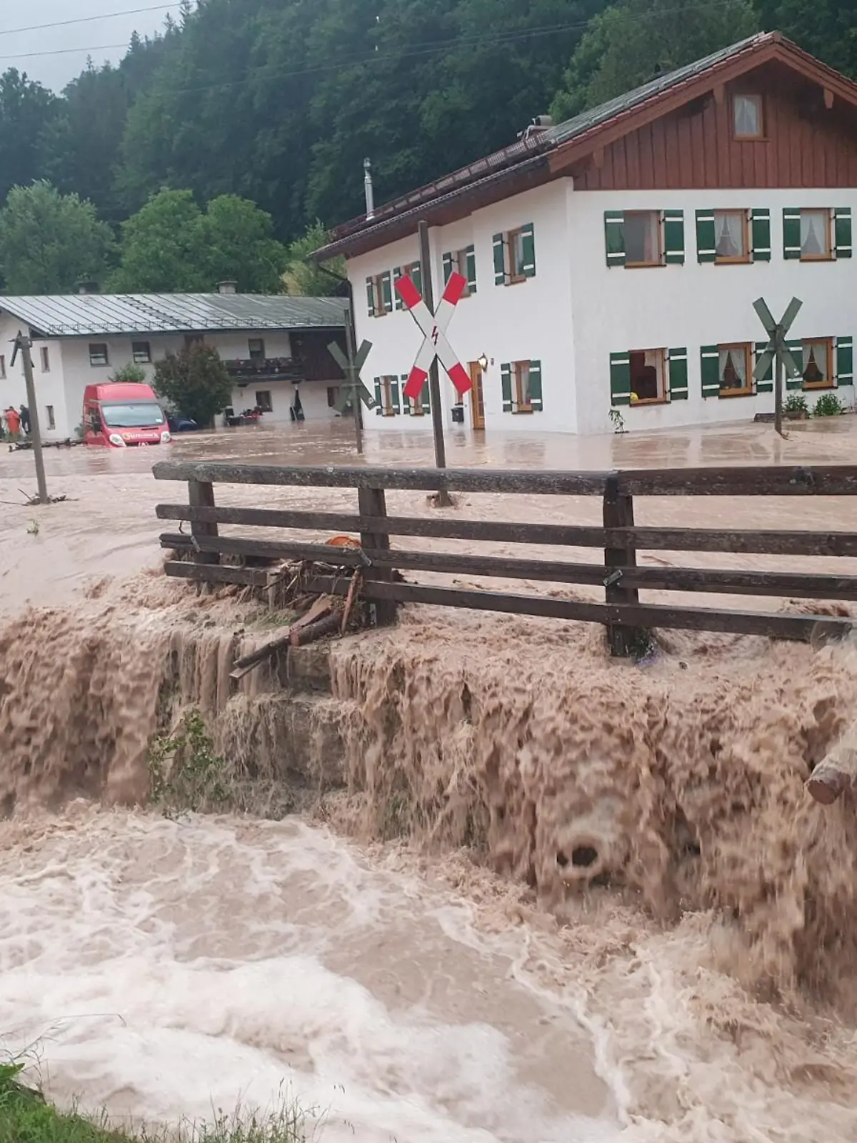dpatopbilder - 17.07.2021, Bayern, Bischofswiesen: Wasser fließt über einen Platz vor einem Haus. Der Landkreis Berchtesgadener Land hat nach starkem Regen wegen Hochwassers den Katastrophenfall ausgerufen. Foto: Kilian Pfeiffer/dpa +++ dpa-Bildfunk +++