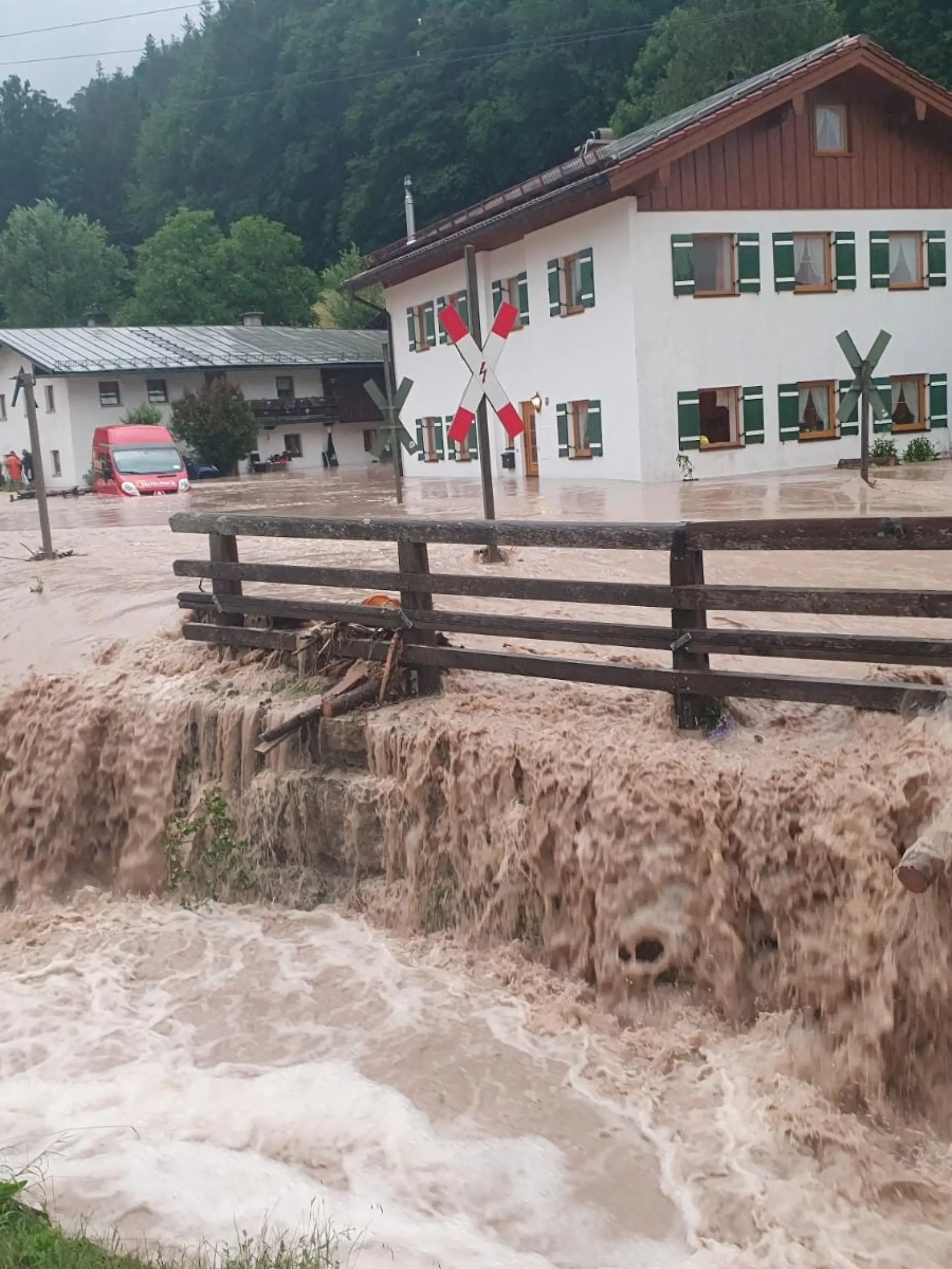 dpatopbilder - 17.07.2021, Bayern, Bischofswiesen: Wasser fließt über einen Platz vor einem Haus. Der Landkreis Berchtesgadener Land hat nach starkem Regen wegen Hochwassers den Katastrophenfall ausgerufen. Foto: Kilian Pfeiffer/dpa +++ dpa-Bildfunk +++