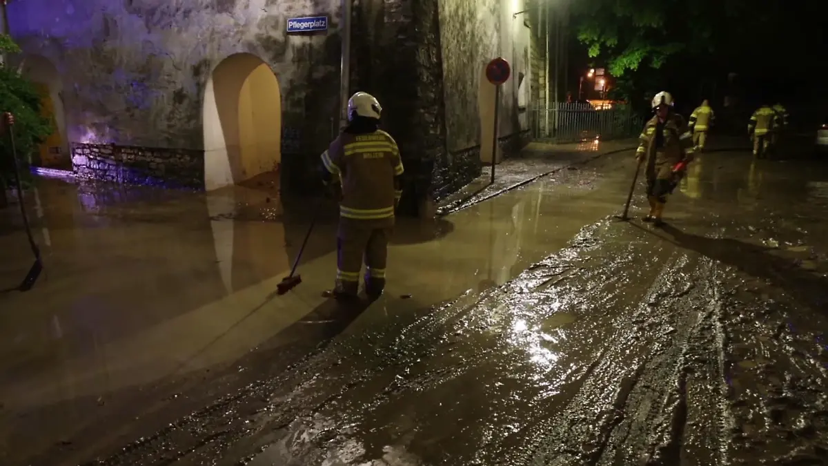 17.07.2021, Österreich, Hallein: Kräfte der Feuerwehr auf einer vom Hochwasser betroffenen Straße. Nach sintflutartigen Regenfällen sind in Österreich Teile der Altstadt von Hallein bei Salzburg überflutet worden. (zu dpa: «Reißende Flut wälzt sich durch Hallein in Österreich») Foto: TNN/dpa +++ dpa-Bildfunk +++